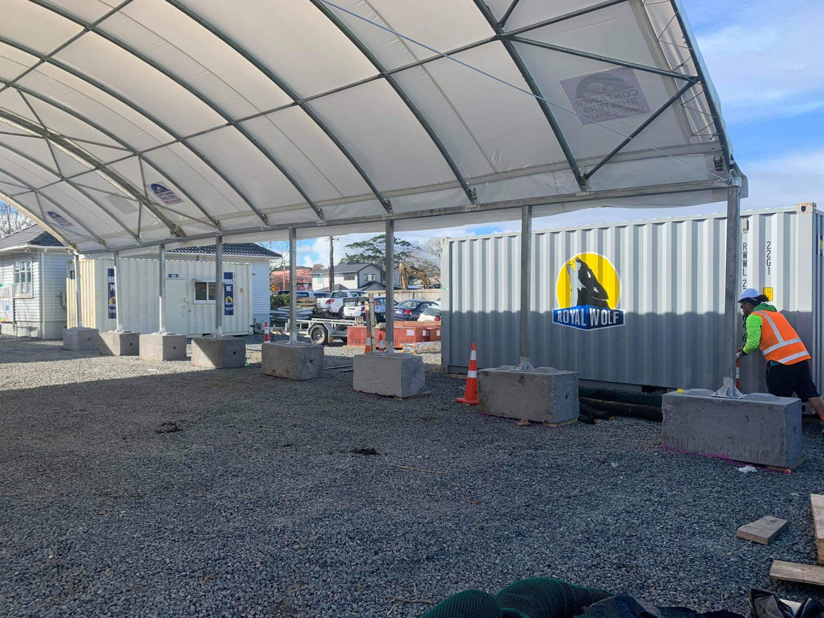 Container shelter on posts mounted to concrete blocks at a construction site